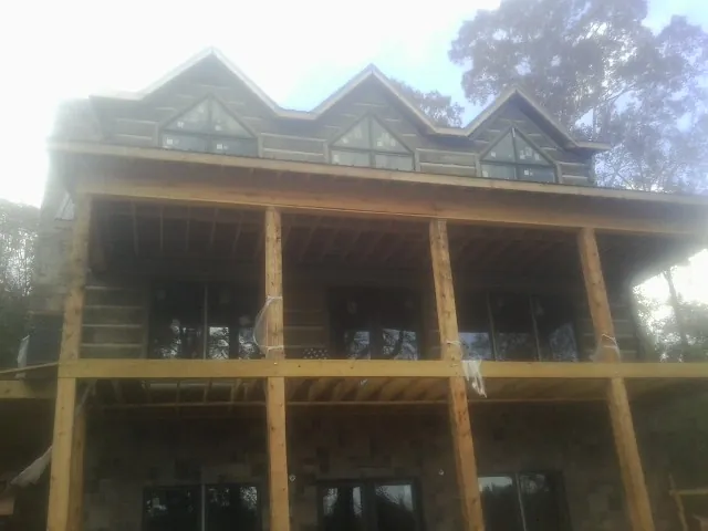 Dormers and porch framing on a large log home under construction — Roof Coating work by our crew in Hot Sulphur Springs