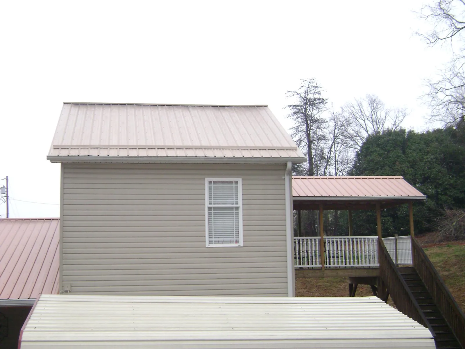 Tan metal roofs on a two story addition and attached porch, from a Roof Replacement job in Hot Sulphur Springs