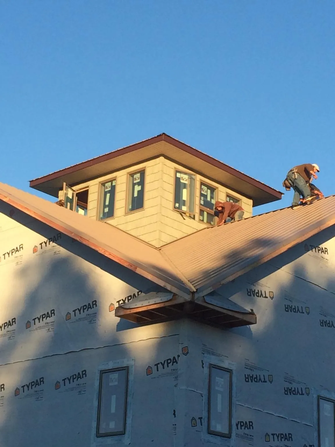Roofers working around a rooftop cupola on a new metal roof at sunset — Roof Waterproofing in Hot Sulphur Springs by Roofing Brothers